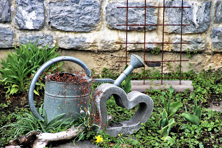 Stahl-Giesskanne und Beton-Herz als Dekoration im Garten